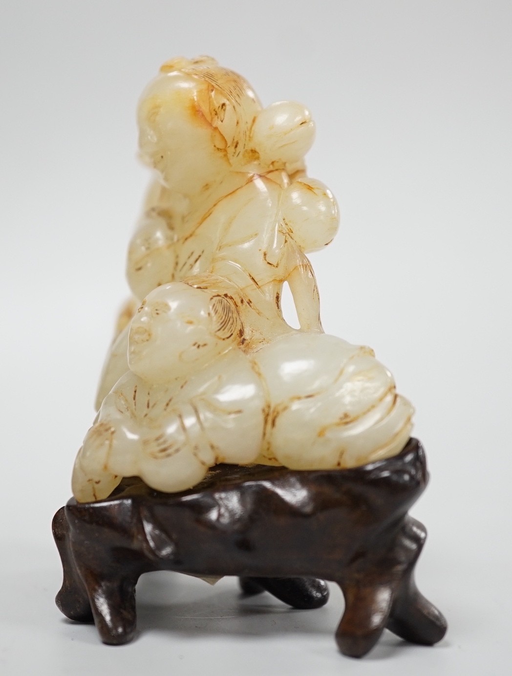 A Chinese white and russet jade group of three boys, 18th/19th century, 7.2 cm, wood stand